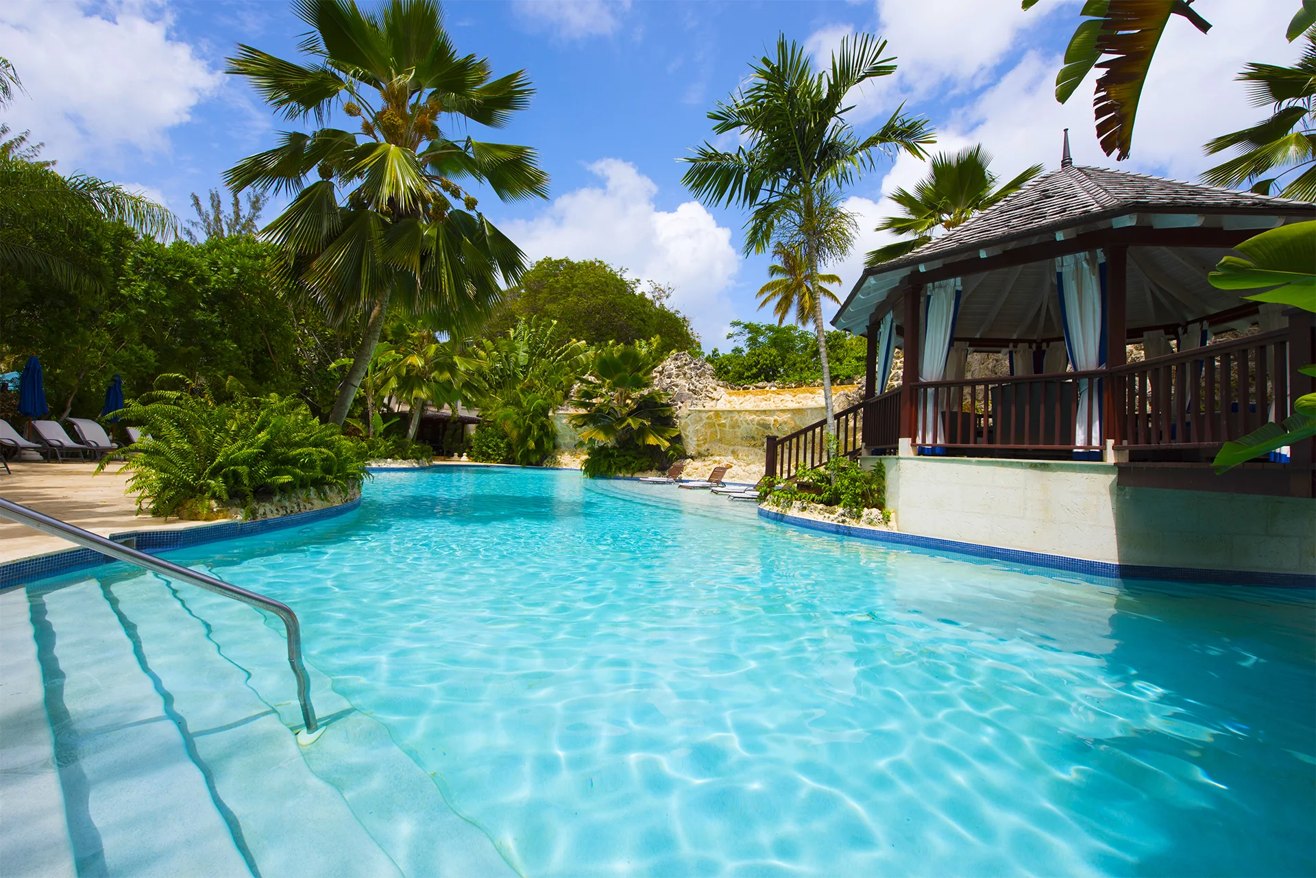 The bright blue swimming pool, palm trees and shaded pavilion at Claridges 3